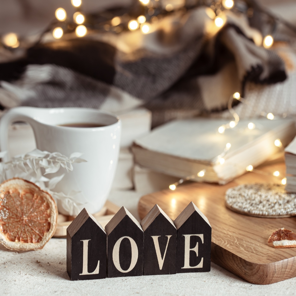 Cozy home composition with decorative word love on blurred background with bokeh.